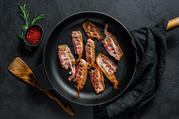 Slices of crispy hot fried cooked bacon. Farm organic meat. Black background. Top view