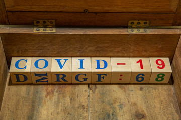 Wooden cubes with word COVID-19 in an old brown box