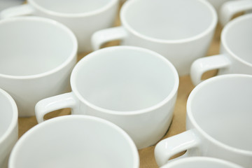 Obraz na płótnie Canvas Modern white ceramic mugs standing nearby.