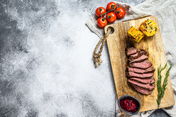Sliced grilled filet Mignon steak on a wooden chopping Board. Beef tenderloin. Gray background. Top view. Space for text