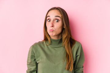 Young caucasian woman posing isolated  shrugs shoulders and open eyes confused.