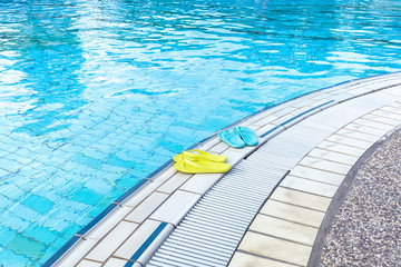 Obraz premium View of yellow and blue flip flops that are standing on a boat by the pool. The concept of summer, vacation, spa, water park, travel