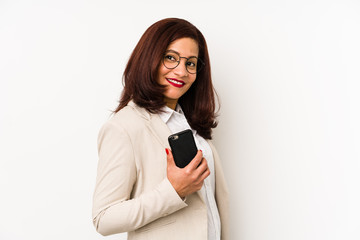 Fototapeta premium Middle age latin woman holding a mobile phone isolated looks aside smiling, cheerful and pleasant.