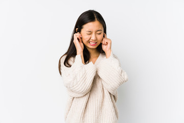 Young chinese woman isolated covering ears with hands.