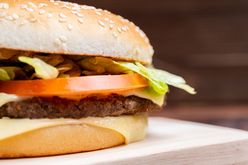 Burger close-up with side on a wooden background.