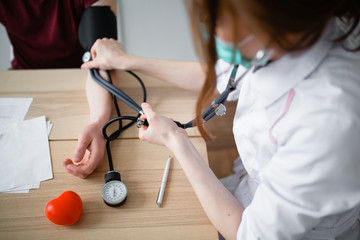 Red-haired doctor measures pressure to a sick patient with signs of coronavirus