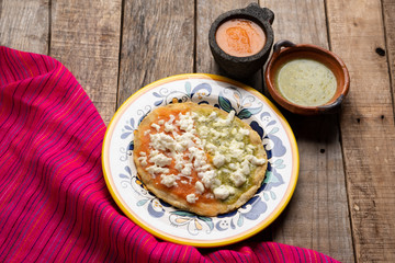 Mexican memela with green and red sauce on wooden background