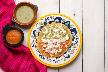Mexican memela with green and red sauce on white background