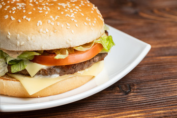 Burger on a white plate and a wooden background with a magnifier.