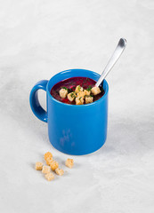 Beetroot soup-puree with sour cream, croutons and greens in a mug
