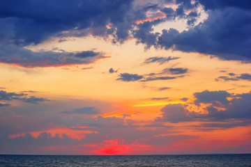 Fototapeta premium Beautiful red summer sunset (sunrise) with floating clouds over the sea