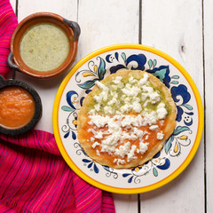 Mexican memela with green and red sauce on white background