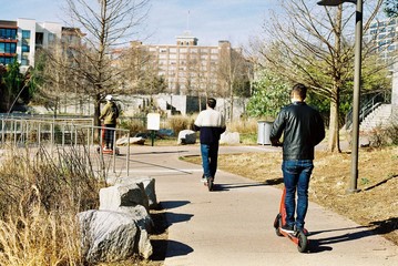 A group of 3 men riding scooters 