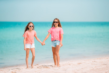 Little happy funny girls have a lot of fun at tropical beach playing together.