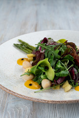Salad with scallops, mango and spinach on white wooden table