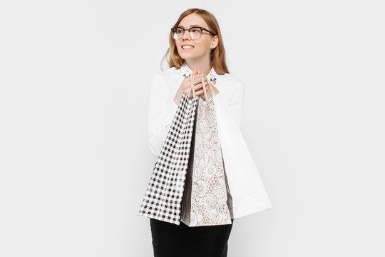The image of a young pregnant businesswoman with glasses, happy girl holding shopping bags, shopping