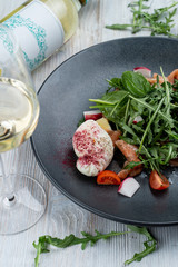 Close up of salad with raw salmon, spinach, arugula and poached egg on light wooden background