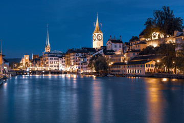 Naklejka na ściany i meble Famous Fraumunster and Church of St Peter with reflections in river Limmat at night in Old Town of Zurich, the largest city in Switzerland