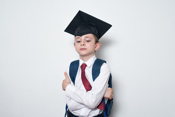 Serious boy in school uniform and graduate hat on white background. Junior High School education