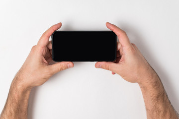 Man holding smartphone in hands. Space for your text. Blank screen.