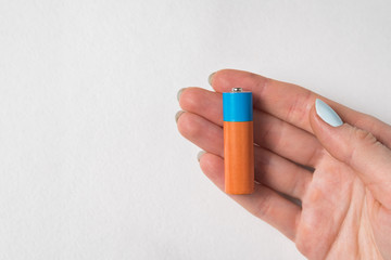 Generic accumulator lies in women's hand. AA battery on white background