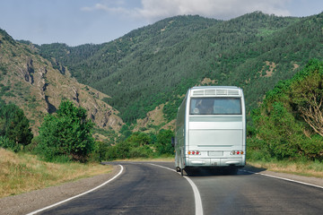 Blank white bus on mountain highway. Back view place your advertising