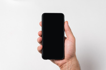 Phone in male hand on white background. Black blank display for text. Copy space