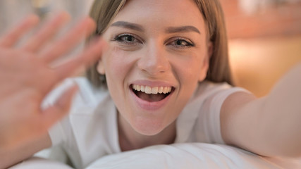 Close up of Cheerful Young Woman doing Video Chat in Bed