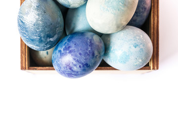Easter eggs. Colored and decorated Easter Eggs  in a wooden box on white background. Easter pattern. Dyed holiday eggs.