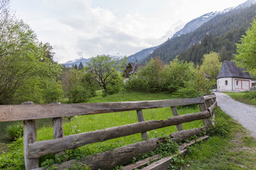 Fototapeta na wymiar Landscape of the Alps, traditional construction with wooden fence and abundant vegetation