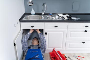Male Plumber In Overall Fixing Sink Pipe