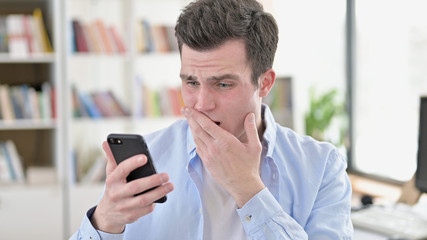 Young Man in Shock by Results on Smartphone