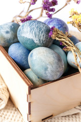 Easter colored eggs in a wooden box on white background. Easter eggs and spring flowers. Holiday pattern.