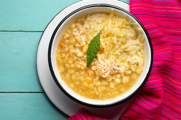 Mexican corn grain boiled also called esquites with cheese and mayonnaise on turquoise background