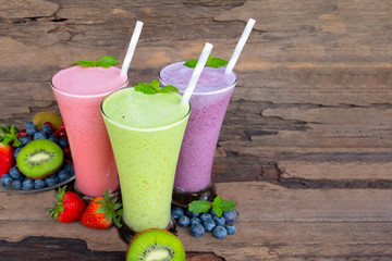 Kiwi strawberry and blueberry smoothies colorful fruit juice green purple and red milkshake blend beverage healthy high protein the taste yummy In glass drink episode morning on wood background.