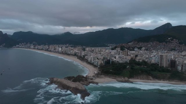 Early morning sideways aerial pan showing Arpoador cliff and wider Rio de Janeiro cityscape in the background