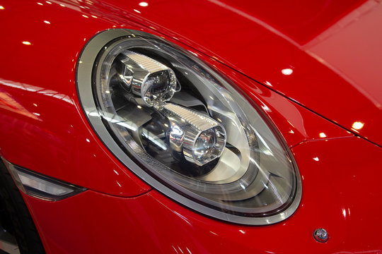 Close up shot of headlight in luxury red car background.