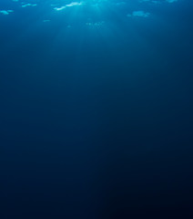 Underwater background in clear blue ocean with sunbeams 