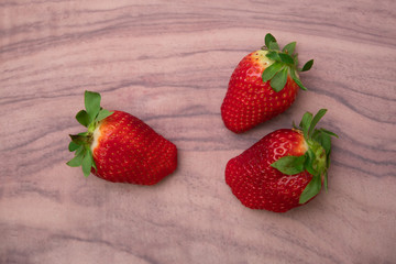 Ripe strawberries on a veined light wooden background