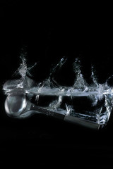 Siilver metal ladle, dipping in water, on black background