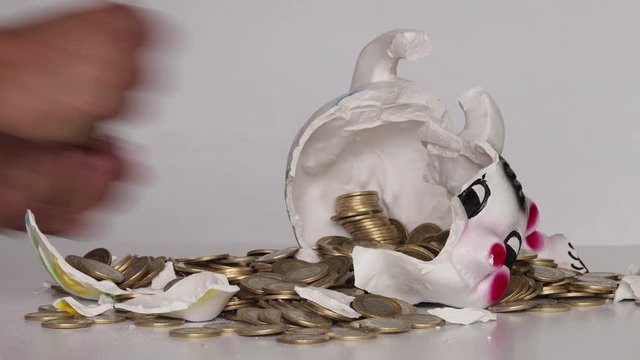 Hands taking coins from broken piggy bank