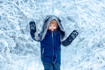 Fototapeta na wymiar Little child boy walking in winter field. Boy dreams of winter time. Happy winter time. Active winter children concept.