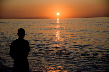Fototapeta premium man observes beautiful sea sunset