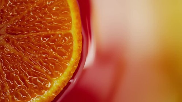 Slice of orange rotating close-up on red background