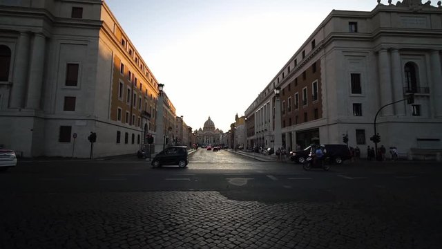 Cars drive in front of Saint Peter’s Basilica in Vatican city, Rome, Italy. Summer tourism landmark & family travel destination in Europe. Religious monument. 
