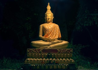 Golden statue of Buddha at a shrine in Wat Wisunarat temple, at night.