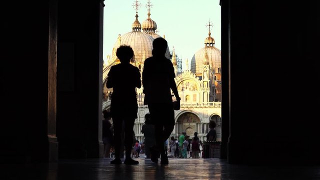 Silhouette of tourists walking to Piazza San Marco, St. Mark’s Basilica. Famous landmark in Venice, Italy. Romantic honeymoon & cruise ship destination in Europe. 
