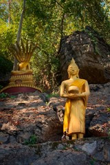 Golden statues of Buddha in the jungle, on the way to the summit of Mt Phou Si, a sacred mountain located in Luang Prabang, Laos.
