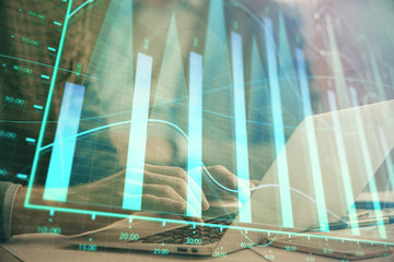 Double exposure of market chart with man working on computer on background. Concept of financial...