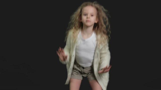 Little girl with blond curly hair, white shirt and white knitted jacket